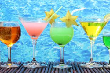 Glasses of cocktails on table on blue sea background