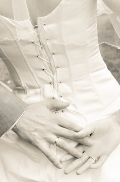 Hands of newlywed couple on the back of bride's corset