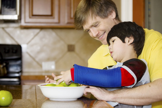 Father helping disabled son with work in the kitchen
