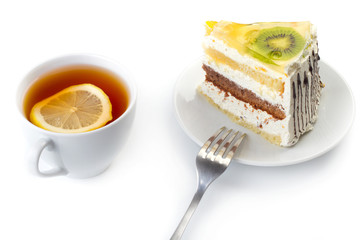 A cup of tea and a piece of tasty creamy cake with fruits