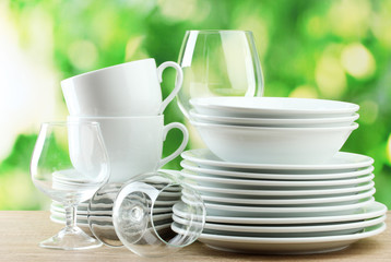 Clean dishes on wooden table on green background