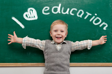 Cheerful smiling child at the blackboard. School concept