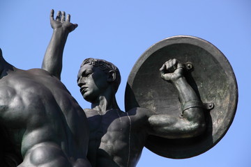A bronze statue of a young soldier with a shield - obrazy, fototapety, plakaty