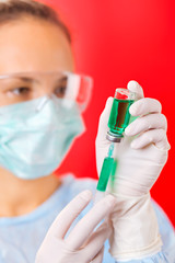 Young woman doctor preparing injection with ampoule and syringe