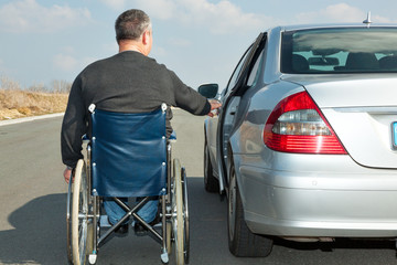 Man in a wheelchair next to his car