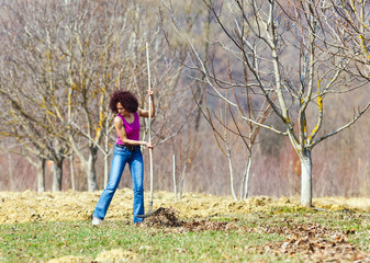 Young woman with a rake in an orchard