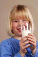 Pequeña niña bebiendo un vaso de leche.