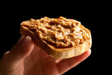 peanut butter toast bread in hand on black background