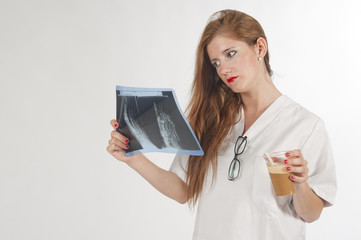 Joven doctora examinando una radiografía tomando café.