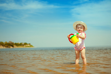 Naklejka premium child with watering-pot on the seashore