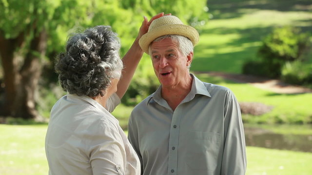 Mature woman bringing a hat to her husband
