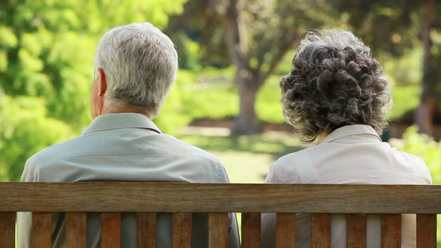 Mature people talking while sitting on a bench