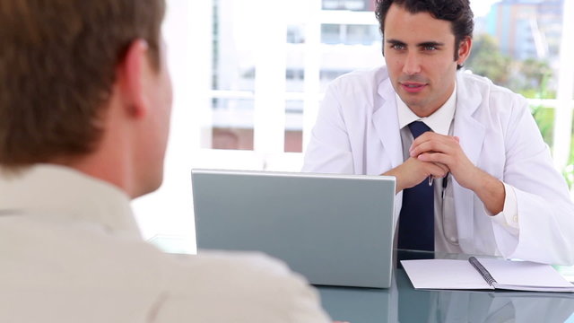 Serious doctor speaking with a patient