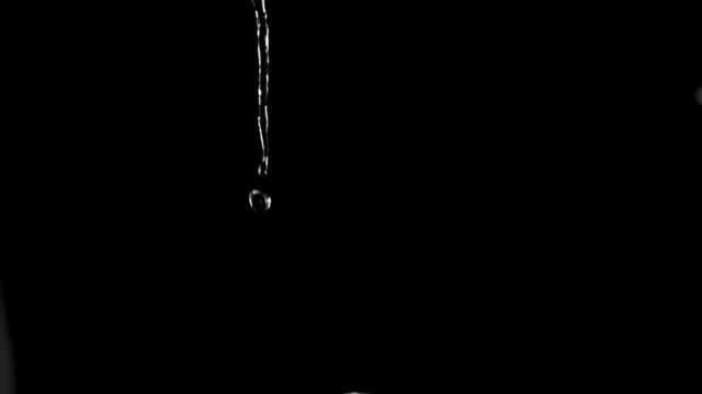 Very thin trickle of water in a super slow motion flowing 