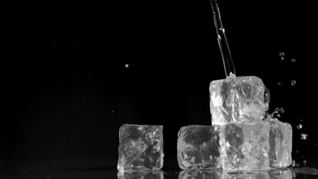 Water being poured in super slow motion onto ice cubes