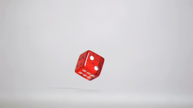 One red dice in super slow motion turning near the floor