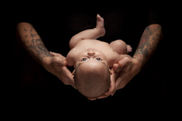 Hands of Father and Mother Hold Newborn Baby on Black