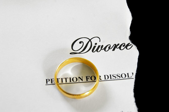 torn divorce decree with gold wedding ring