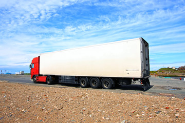 A big red and white lorry against blue sky