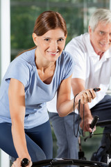 Lachende Frau mit Stoppuhr im Fitnesscenter