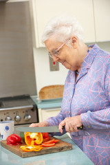 Senior woman chopping vegetables in domestic kitchen