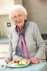 Senior woman enjoying meal in kitchen