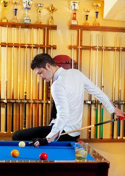 Billiard winner handsome man playing with cue and balls at club