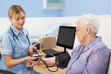 UK nurse taking senior woman's blood pressure