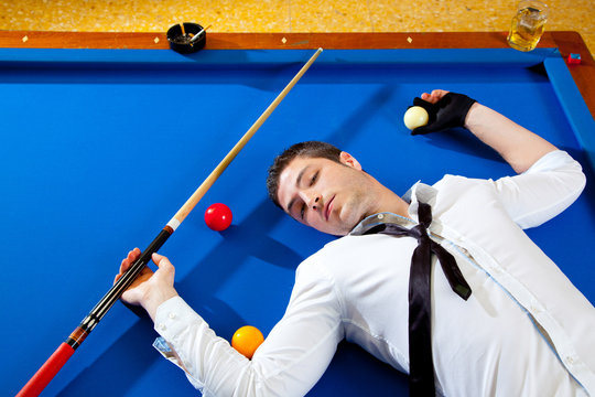 billiard young man player lying on pool blue table