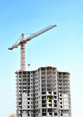 Building crane and building under construction against blue sky