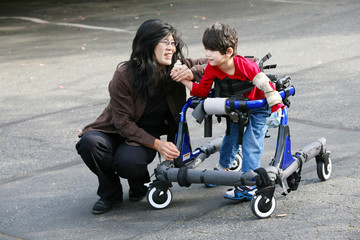 Mother with disabled son walking outdoors with walker