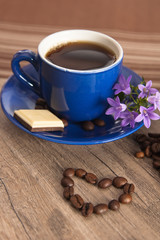 Cup of coffee with beans on old wooden surface