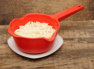 Pasta in red colander on table