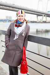 Obraz premium Portrait of happy young female with red bag on embankment