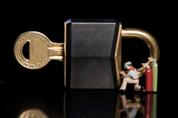 Miniatur arbeiter schweissen ein Schloss zu