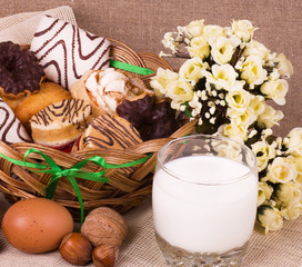 Tasty cakes in basket, eggs, glass of milk and eggs