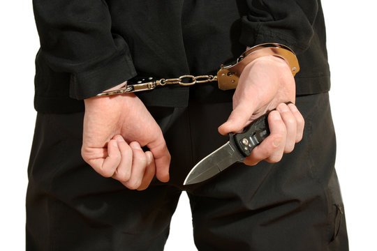 Bandit in black mask handcuffed isolated on white