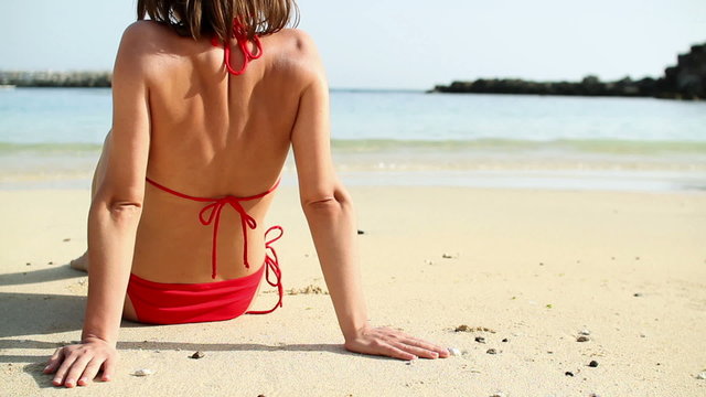 Sexy woman in red bikini sunbathing on the beach
