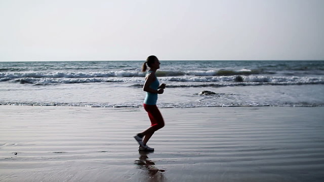 Young woman jogging on the beach, slow motion