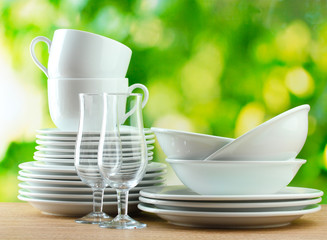 Clean dishes on wooden table on green background