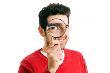 Smiling young man looking through magnifying glass, isolated on