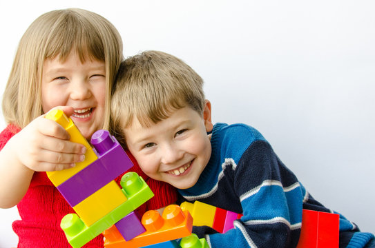 Two happy children play with blocks