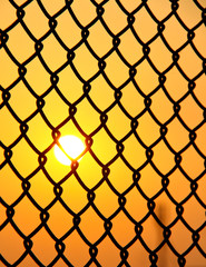 Fototapeta premium chain link wire fence with sun rise