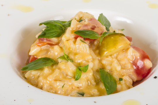 photo of delicious risotto dish with herbs and tomato on white b