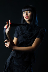 Young brunette lady in black dress posing on dark background