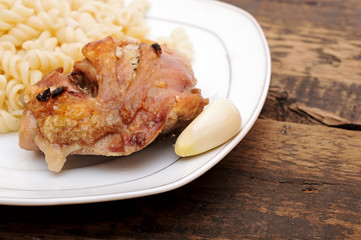 A plate of pasta and chicken with garlic on wood background
