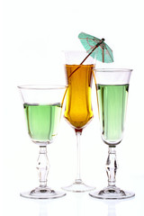 Three wineglasses are filled with colored beverages
