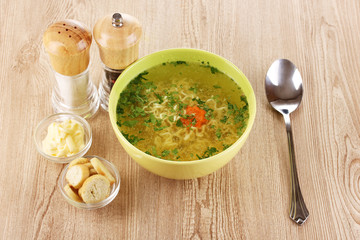 Tasty chicken stock with noodles on wooden background