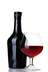 Glass of brandy and bottle isolated on white