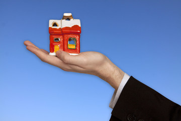 The Hand of the Businessman with the House on the blue Sky